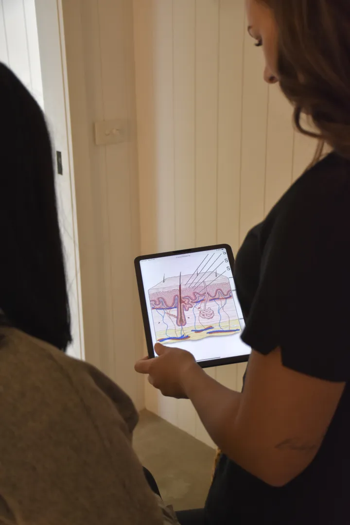 Clinic consultation showing skin diagram on a tablet.