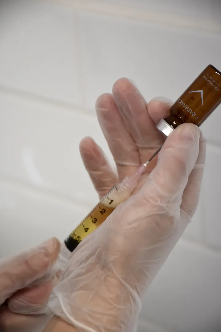 Preparing syringe with medicinal vial in a clinical setting.