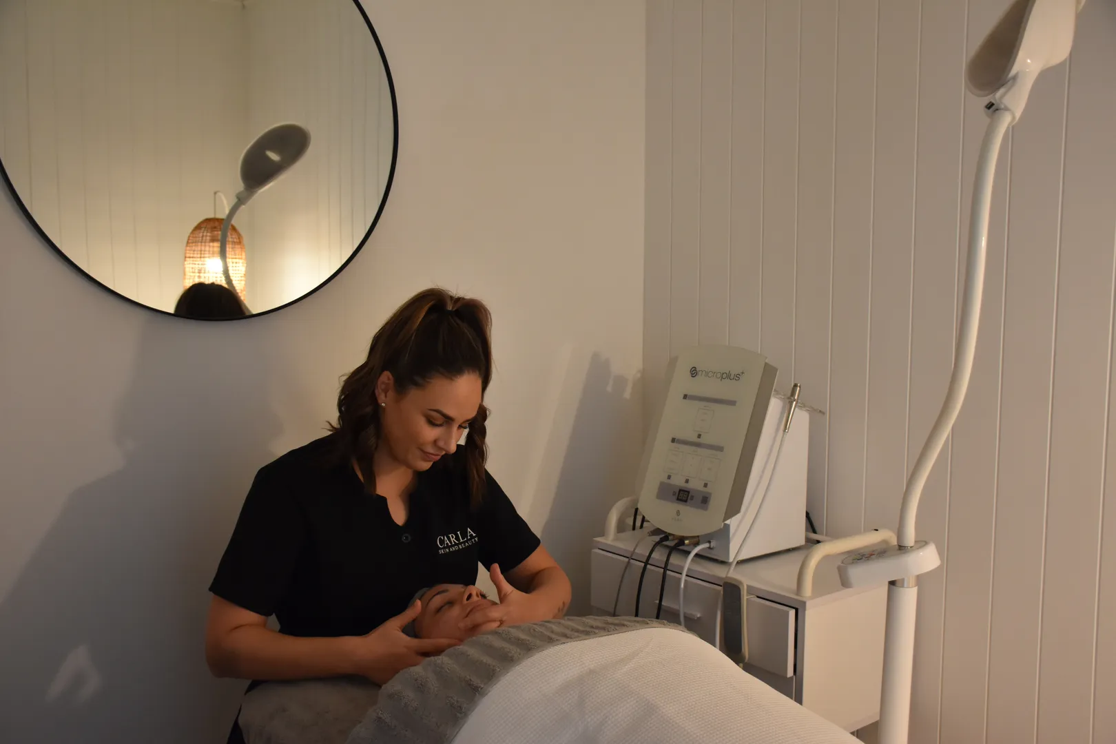Esthetician performing facial treatment in spa room.